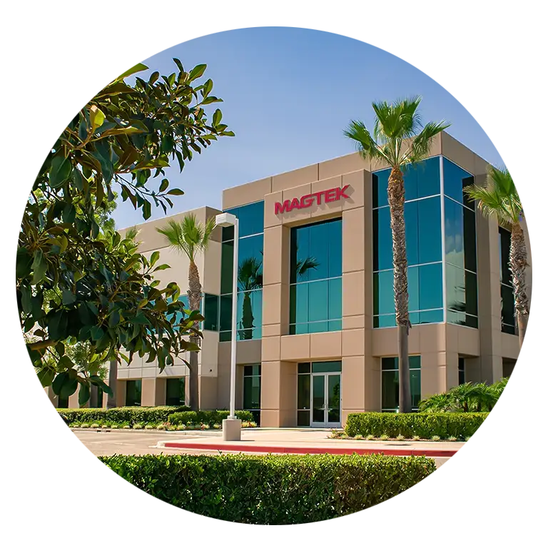 A bright and sunny image of MagTek's headqaurters in Seal Beach, California. The building is surrounded by palm trees and MagTek's building says MagTek at the top in large letters.